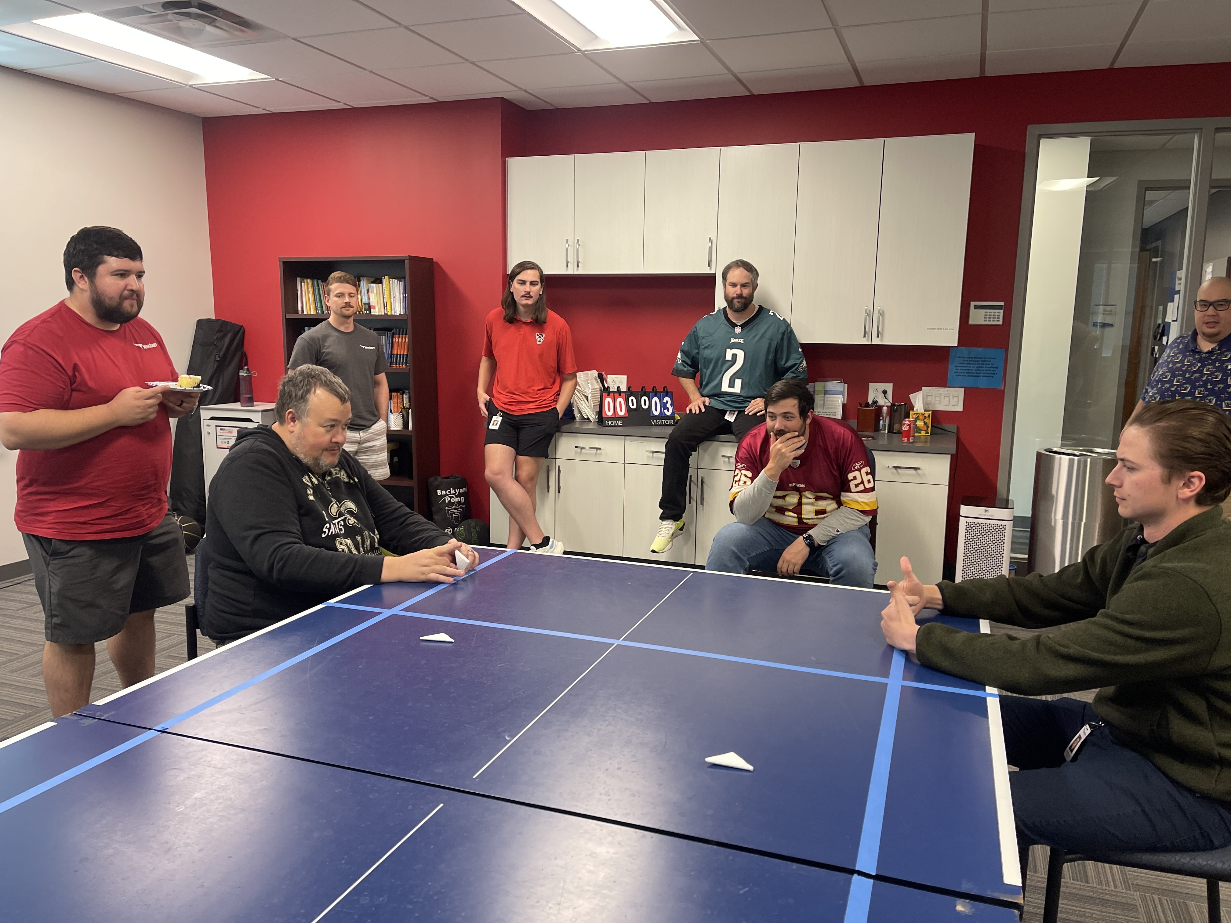 Team members enjoying a fun game of paper football in the office.